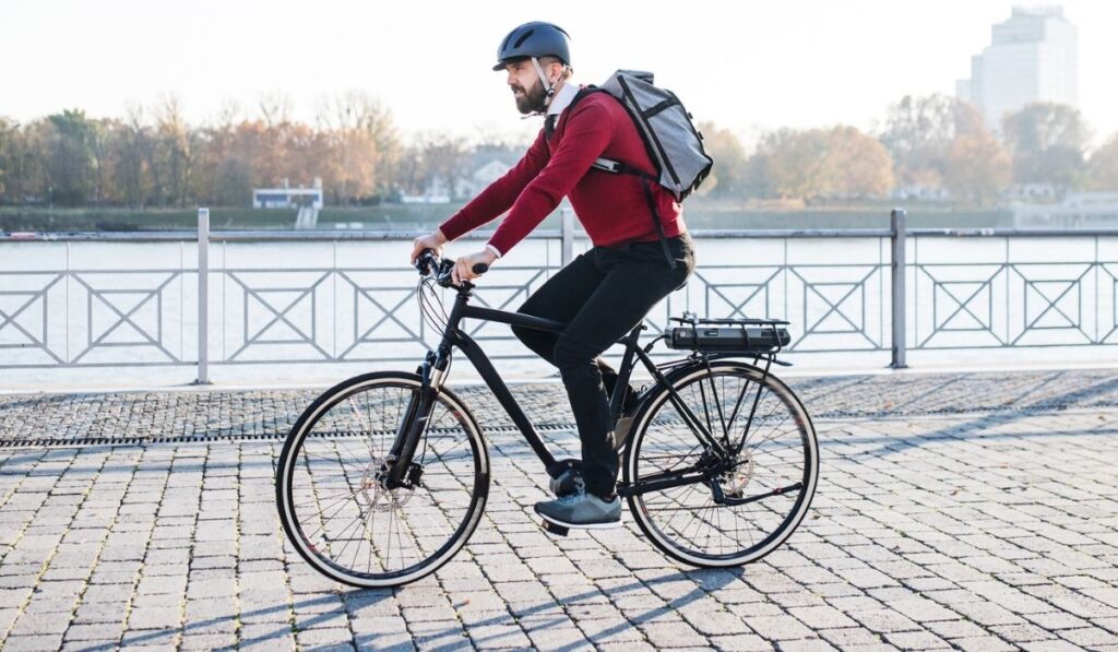 Hipster businessman commuter with electric bicycle traveling to work in city