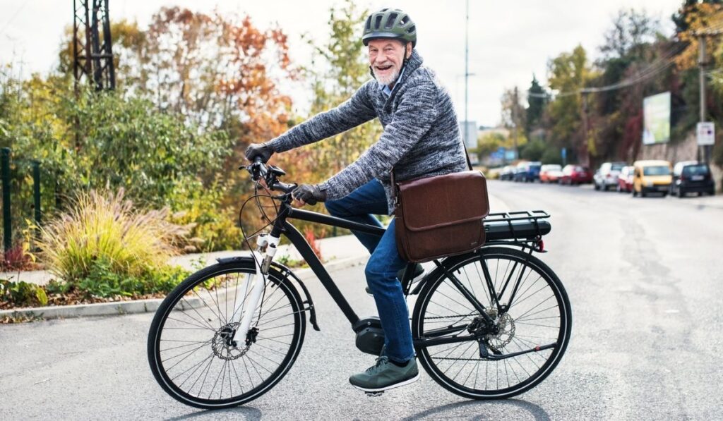 Active senior man with electrobike cycling outdoors in city