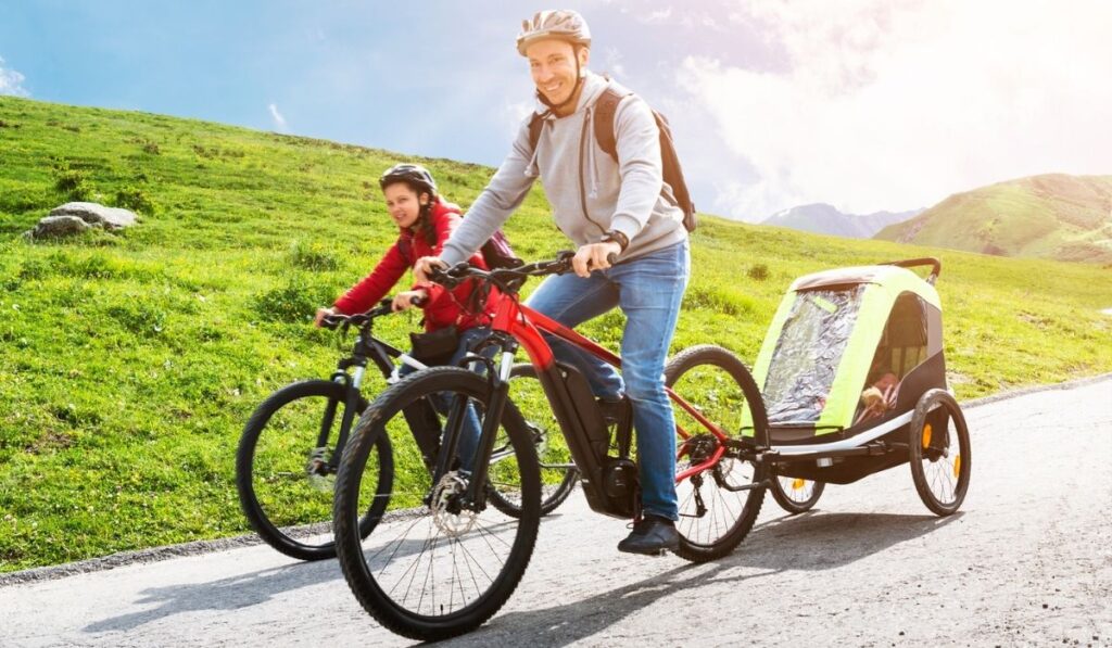 Family With Child In Trailer Riding Mountain Bikes