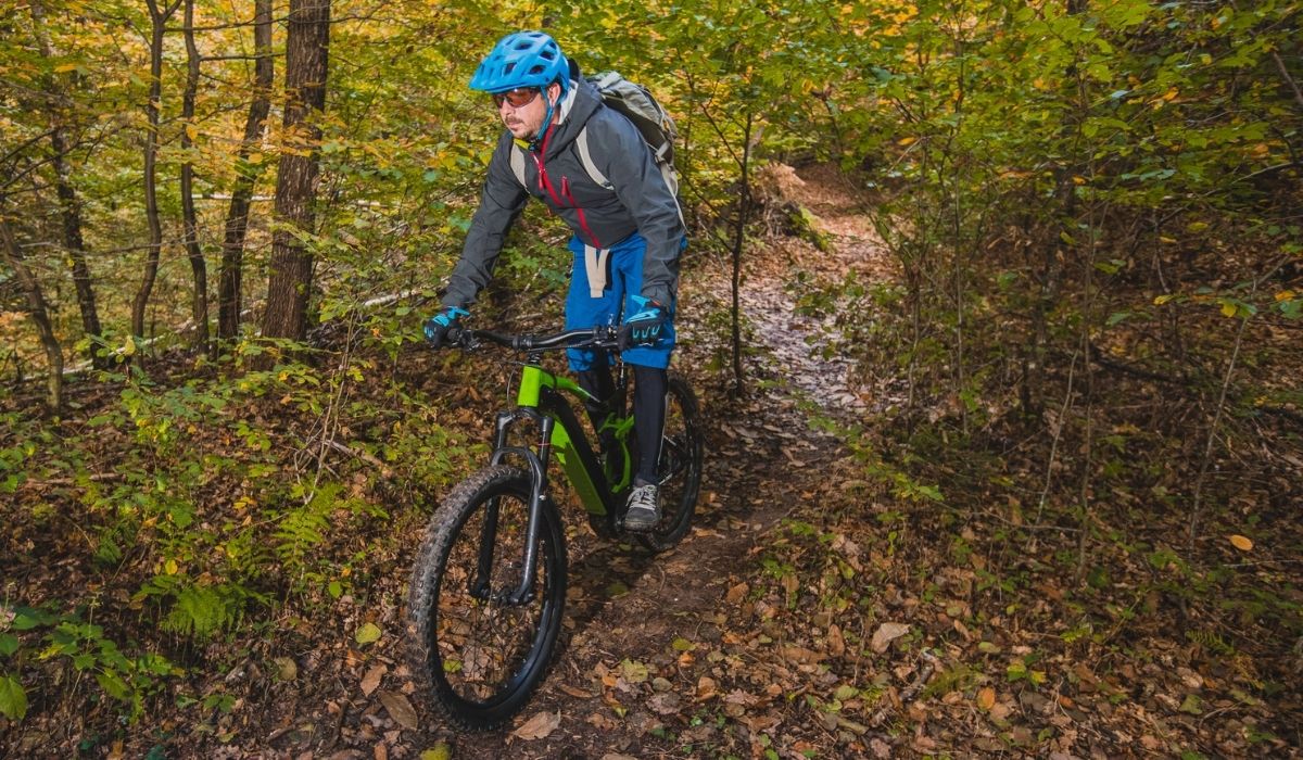 Biker riding downhill with a modern electric bicycle or mountain bike in autumn