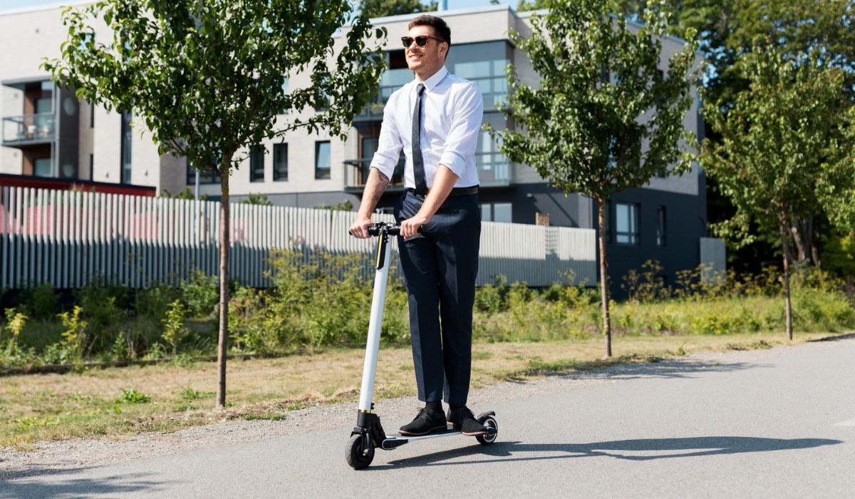 Young businessman riding electric scooter outdoors