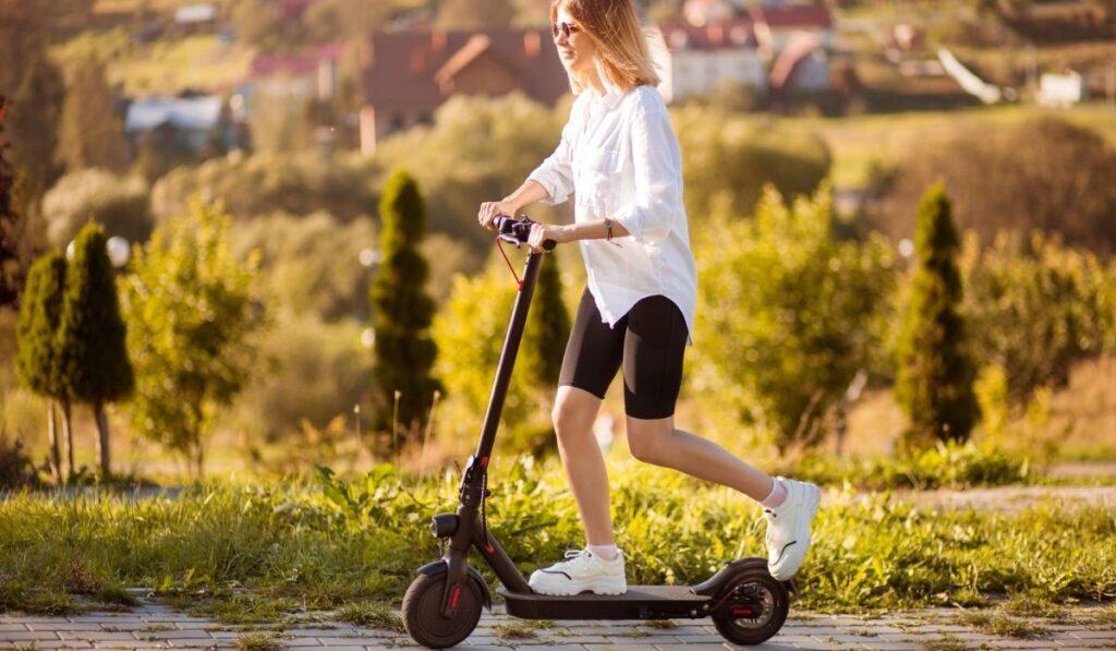 Young beautiful stylish woman riding electric scooter to work 