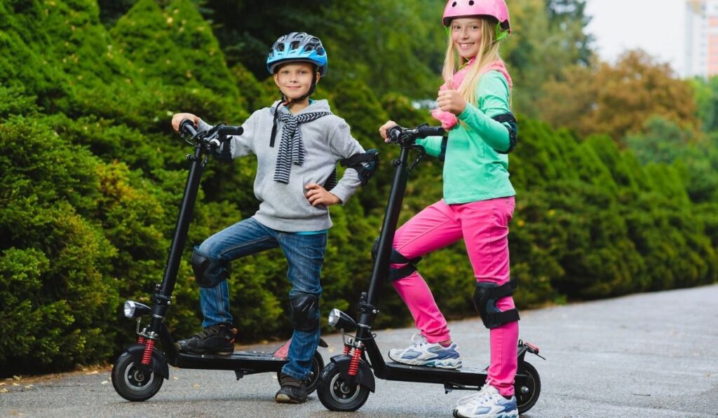 Happy kids standing on electric scooter outdoor 