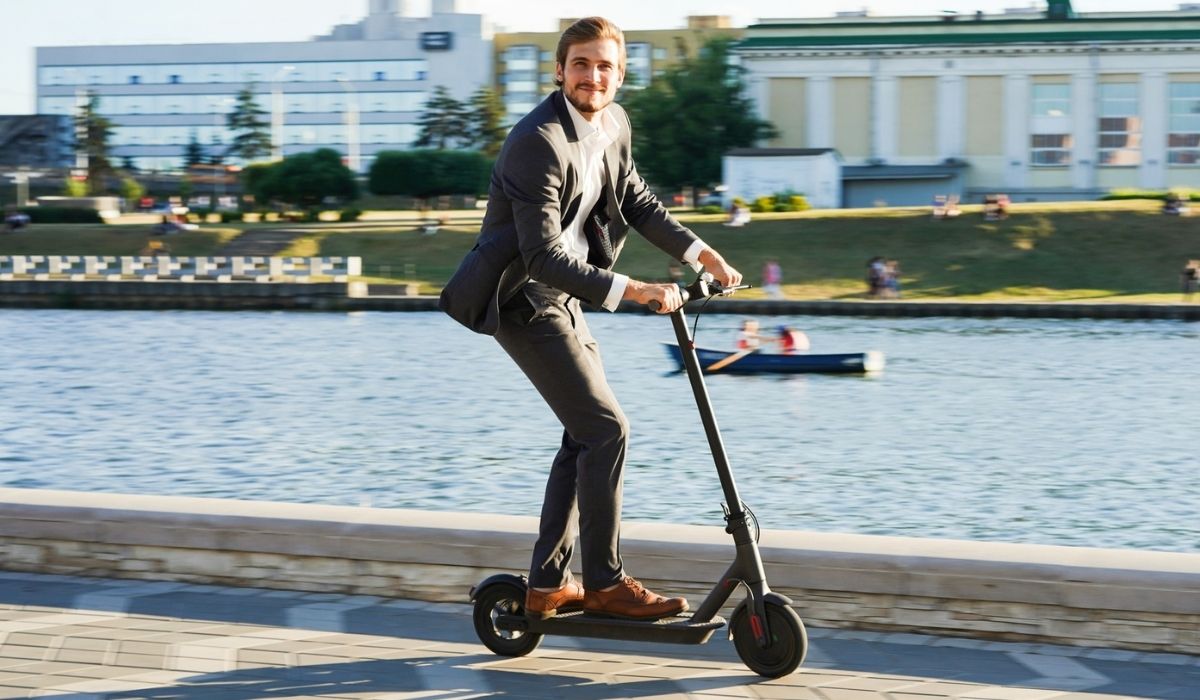 Young business man in a suit riding an electric scooter on a business meeting