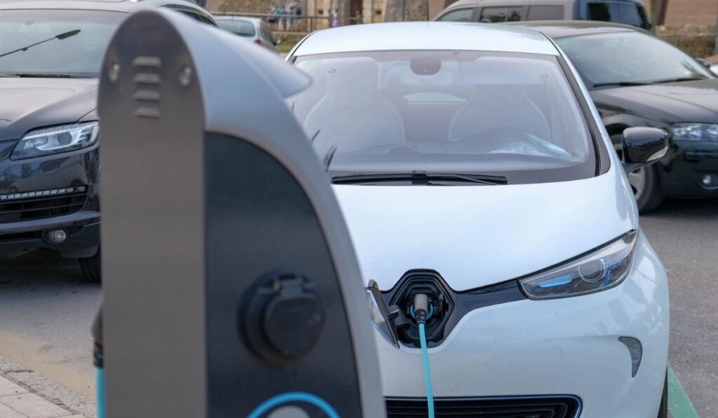 Close up of white Electric car at charging station with power cable