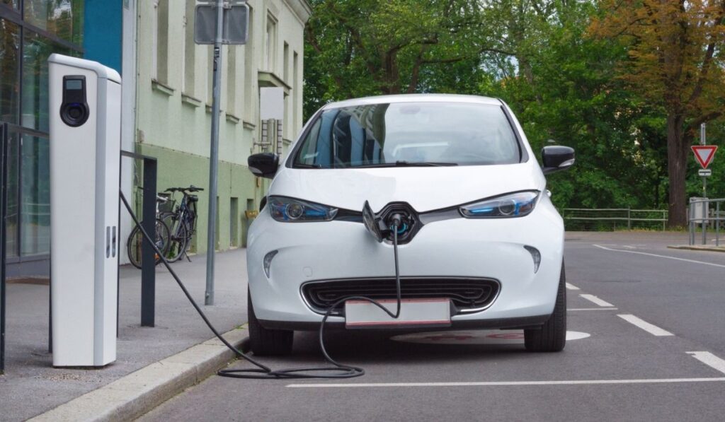 Modern electric car plugged in charging on the street station