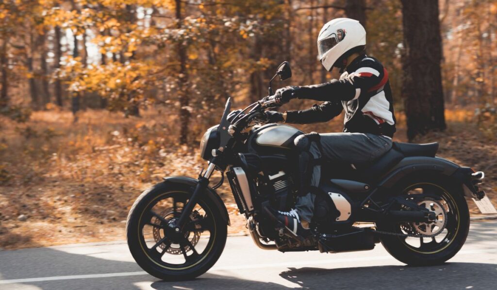 A young guy in a helmet is riding on a forest road on an electric motorcycle