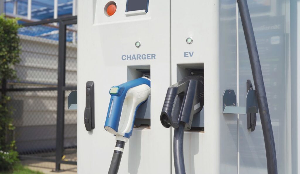 Hand pulling in cable from EV car charger or electric vehicle station