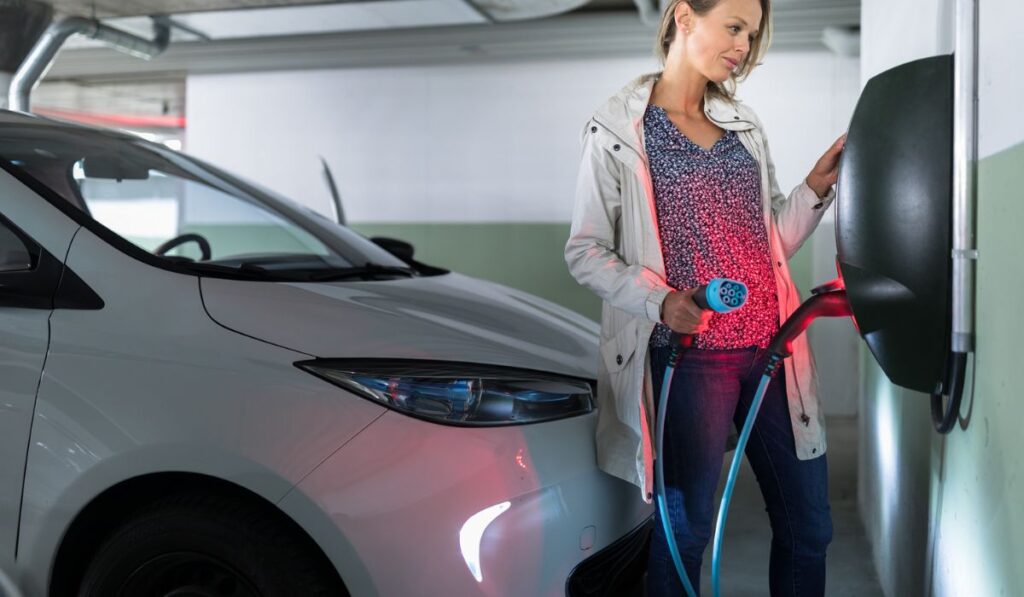 Young woman charging an electric vehicle in an underground garage